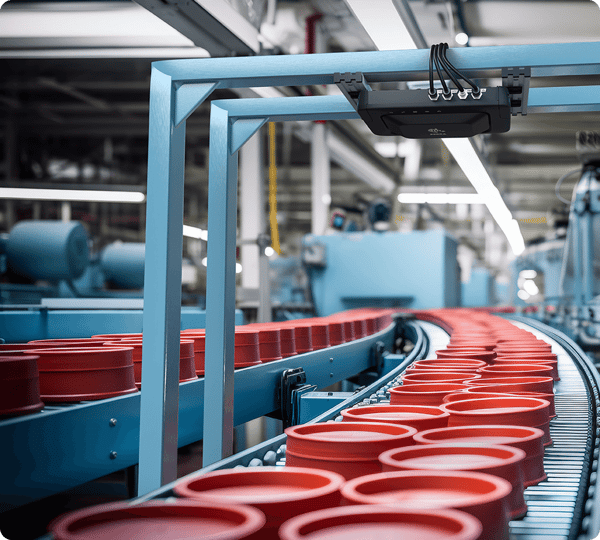 Red plastic containers move along a conveyor belt in a brightly lit, modern factory setting.